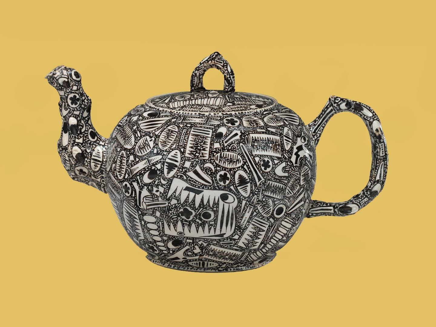 A small, wide, black-and-white teapot covered in tightly packed doodle-like drawings